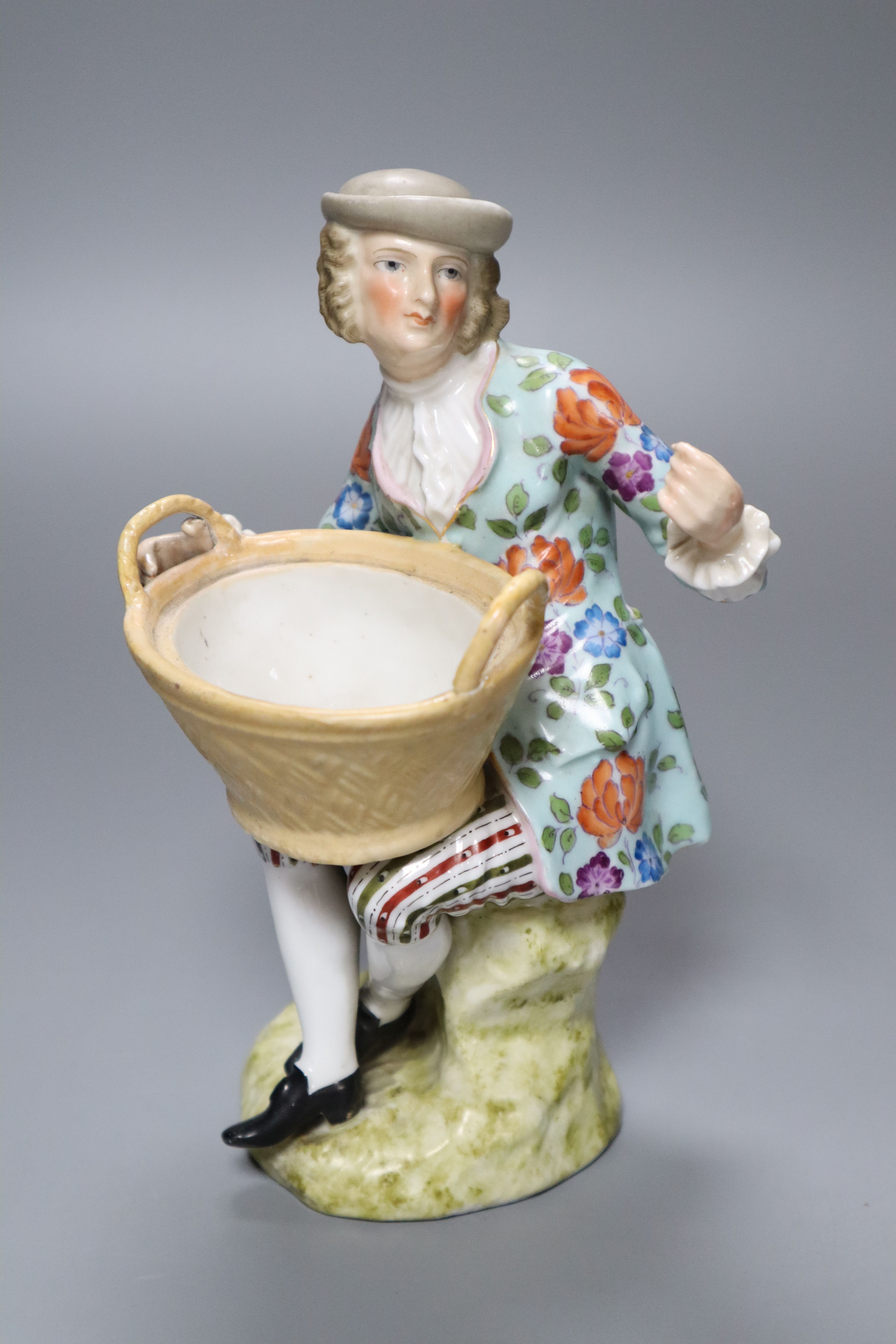 A Sitzendorf porcelain figure of a youth holding a basket, after a Meissen original by J.J. Kaendler, height 19cm